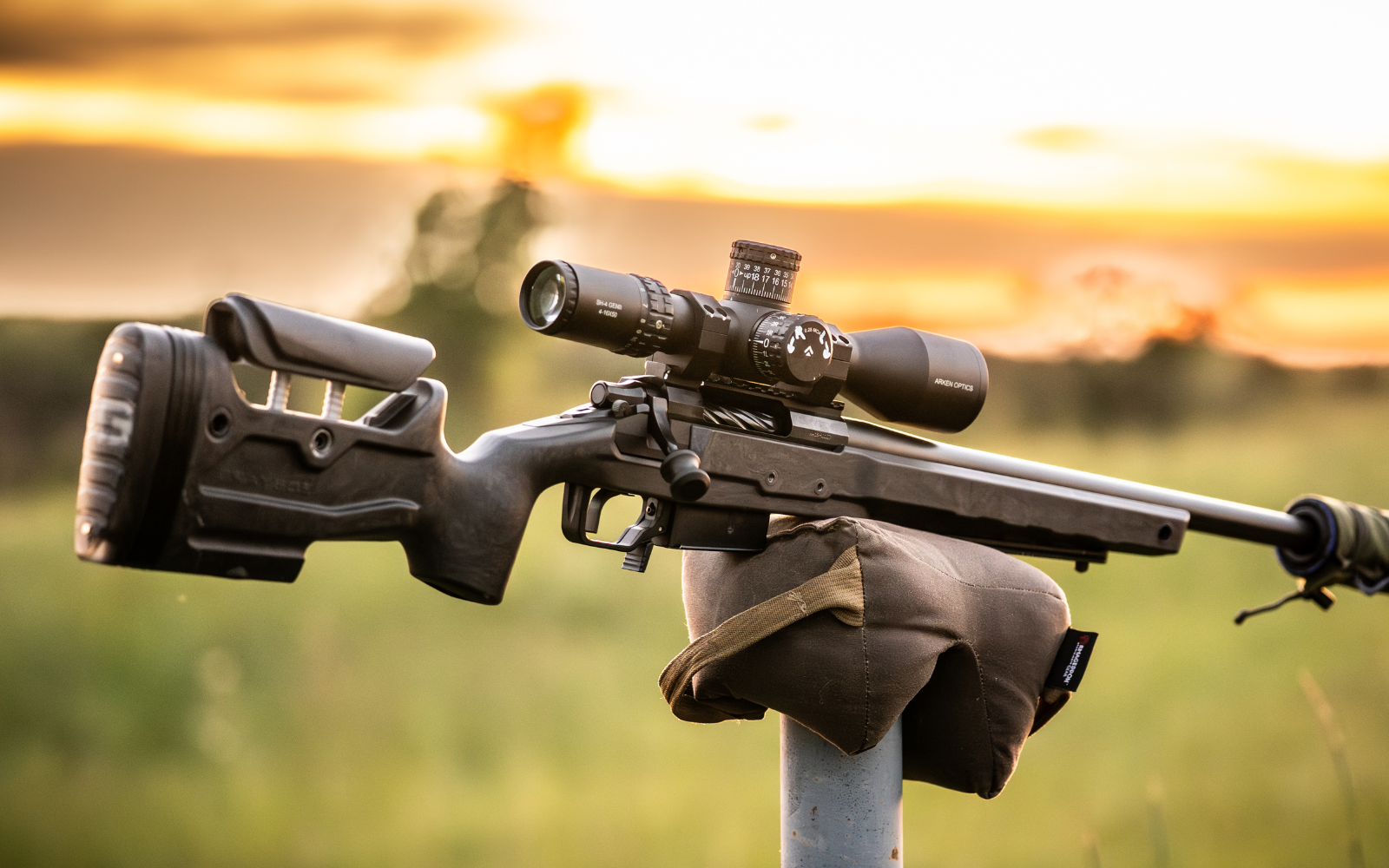 Shooter aiming a rifle with a scope in a natural setting